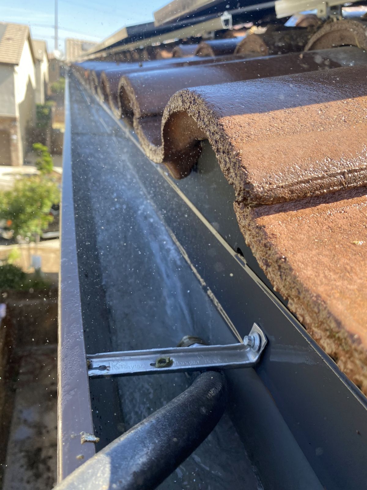 A rain gutter running clear and clean along a tile roofline after cleaning